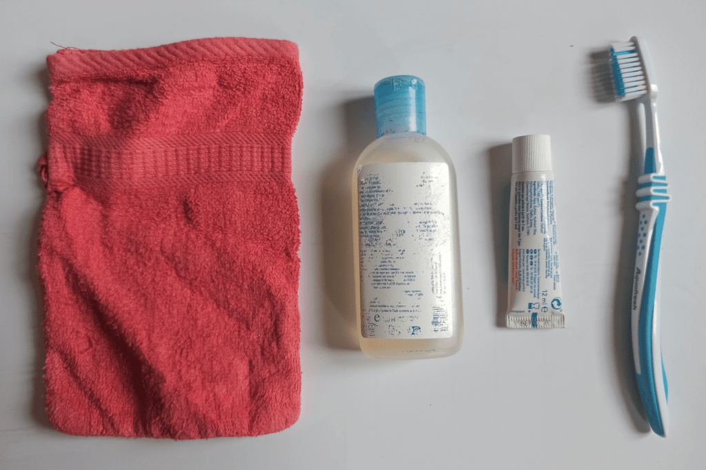 petite trousse d'hygiène en bivouac : savon liquide, gant, brosse à dents et dentifrice